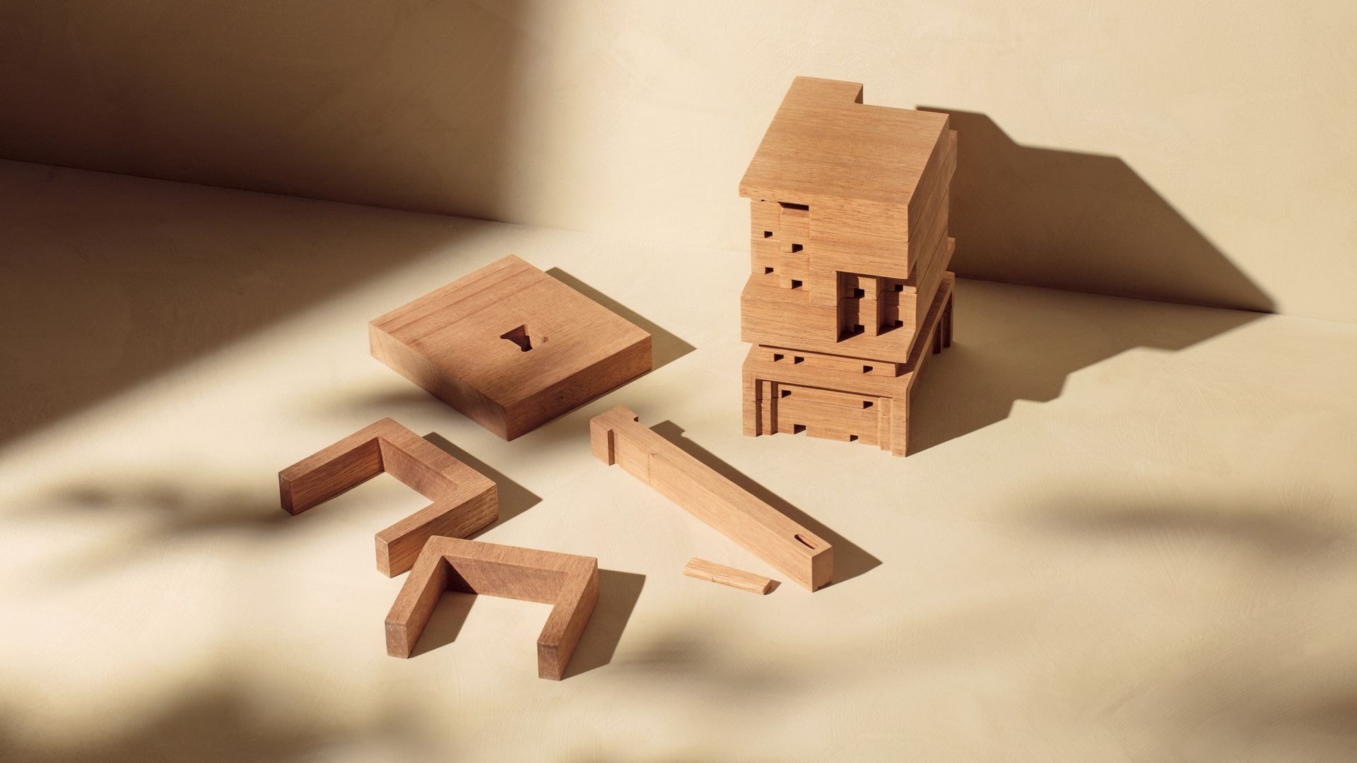 A wooden BeeHome and a few parts on a beige background. Sunlight shines creates shadows on and around the object.