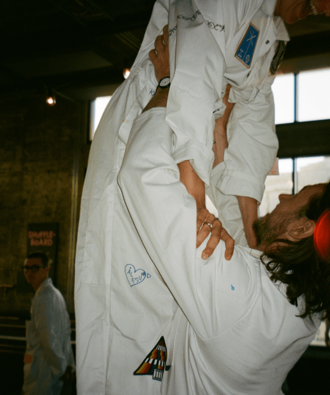 A person in a white coat holding up another person also in a white coat