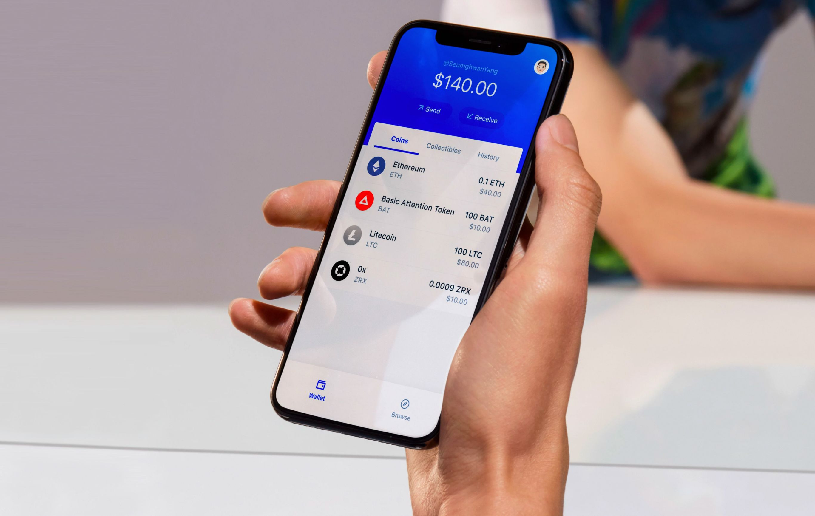 A person holding up a mobile phone with the Coinbase app open