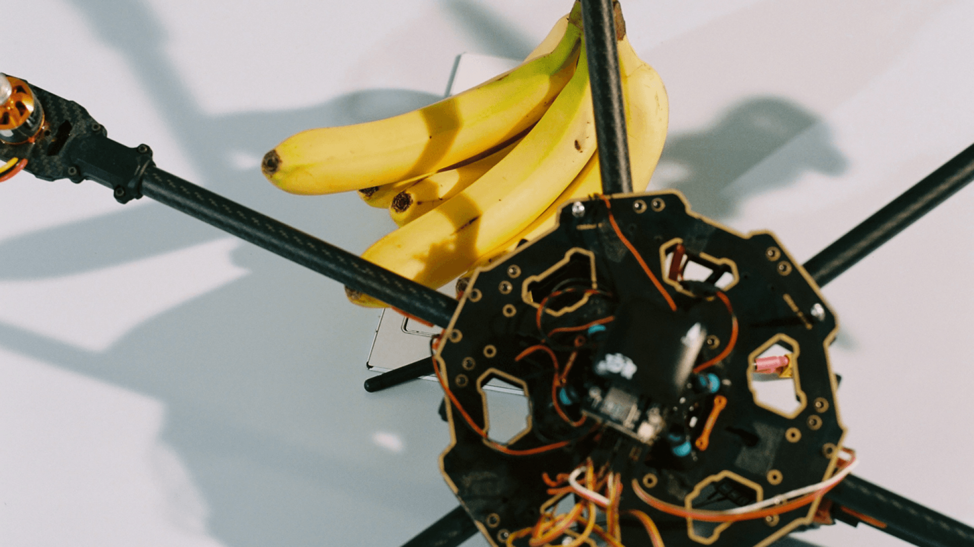 Image of a deconstructed drone on a table with some bananas next to it.