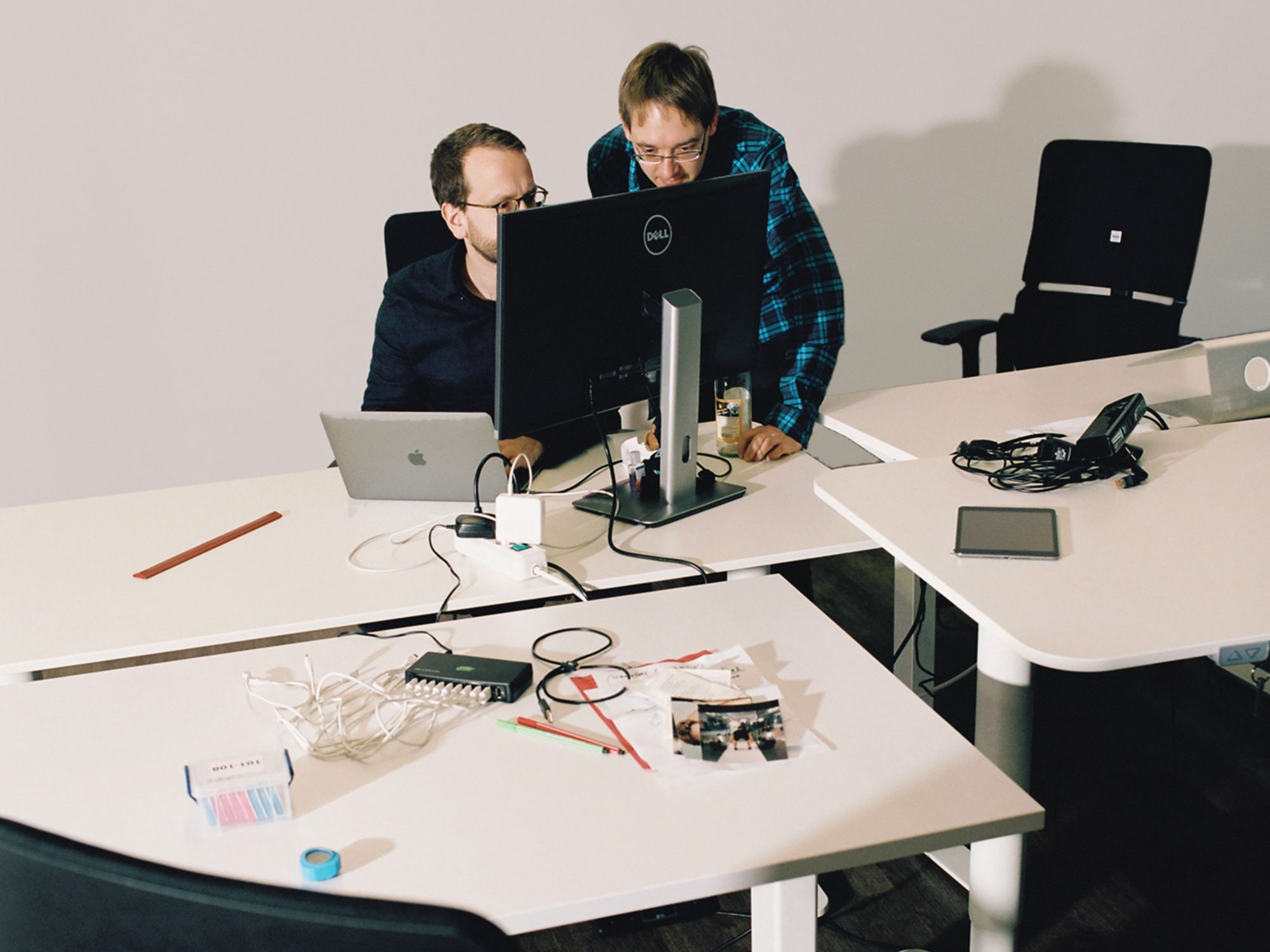 Two people pair-programming behind a computer display on a messy desk