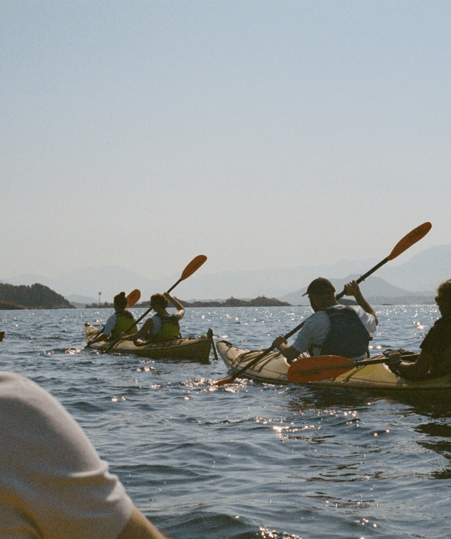 People in two kayaks on a lake with some mountains in the background