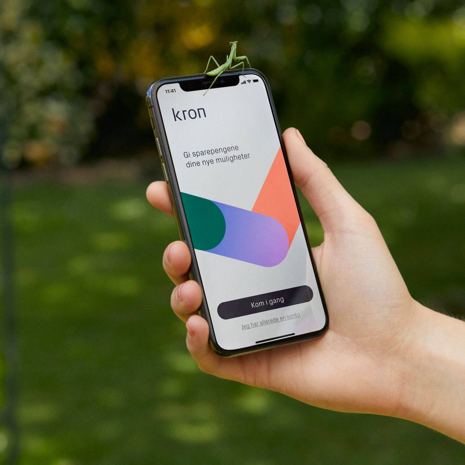 A hand holds a mobile phone that displays the Kron onboarding screen, featuring the logo and the data-driven graph.