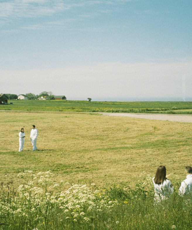 Analog photo of a big grass field with two groups of two people in white coats