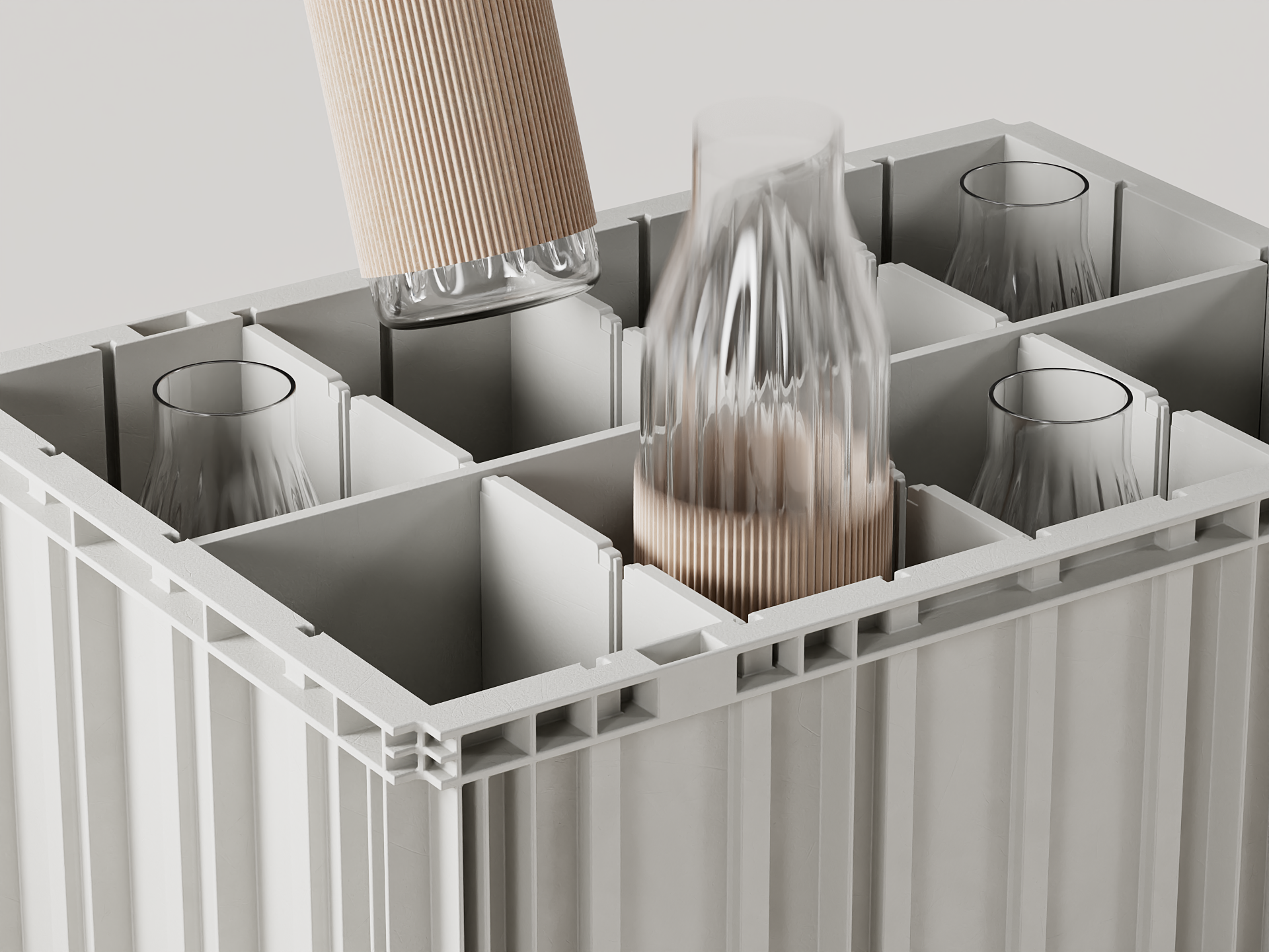 A close-up shot of a grey, industrial-style crate divided into multiple compartments. Several clear glass carafes with ribbed, tan-colored lower sleeves are being placed inside, with one partially lifted above its slot.