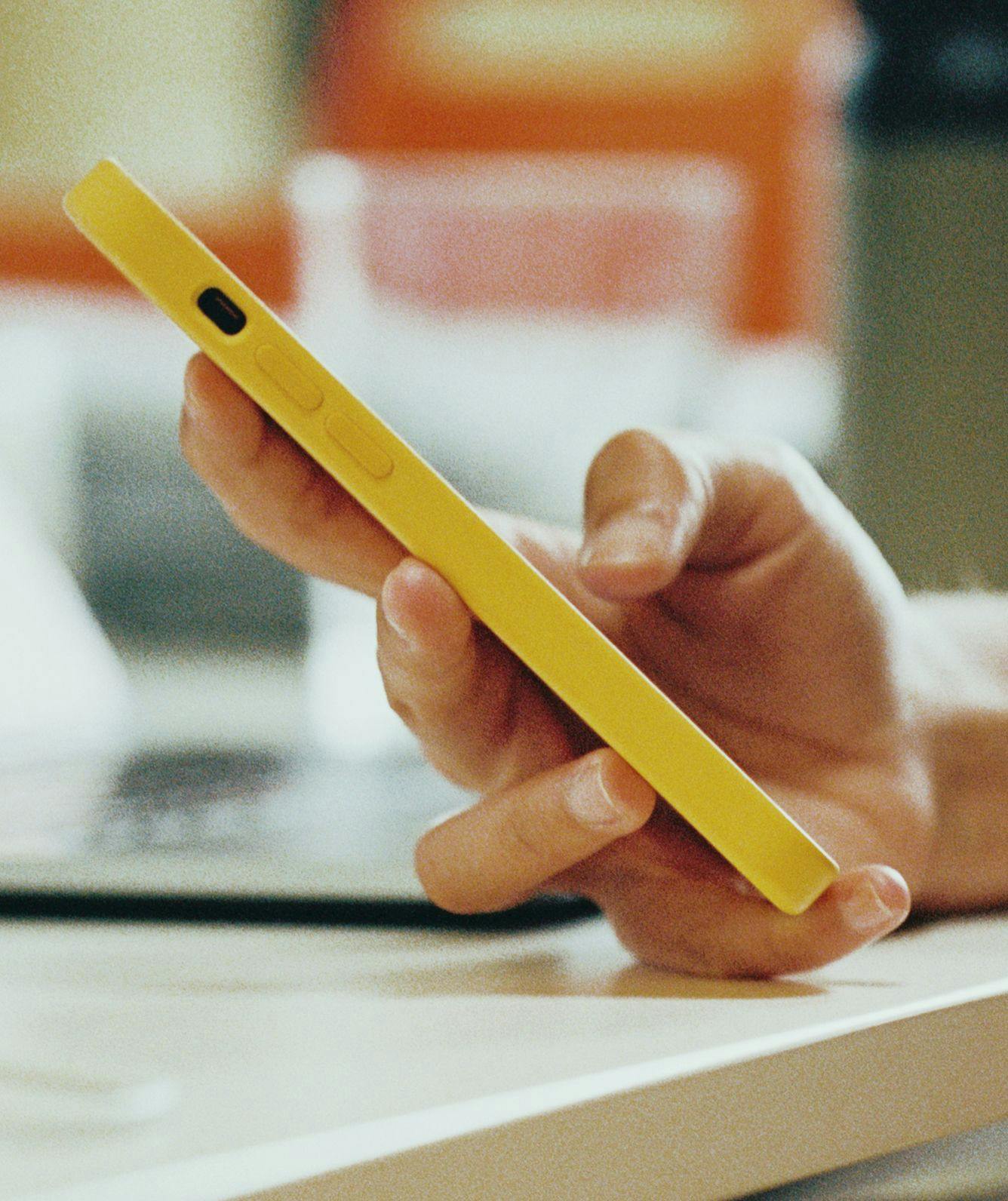 Close-up of a human hand holding a yellow phone