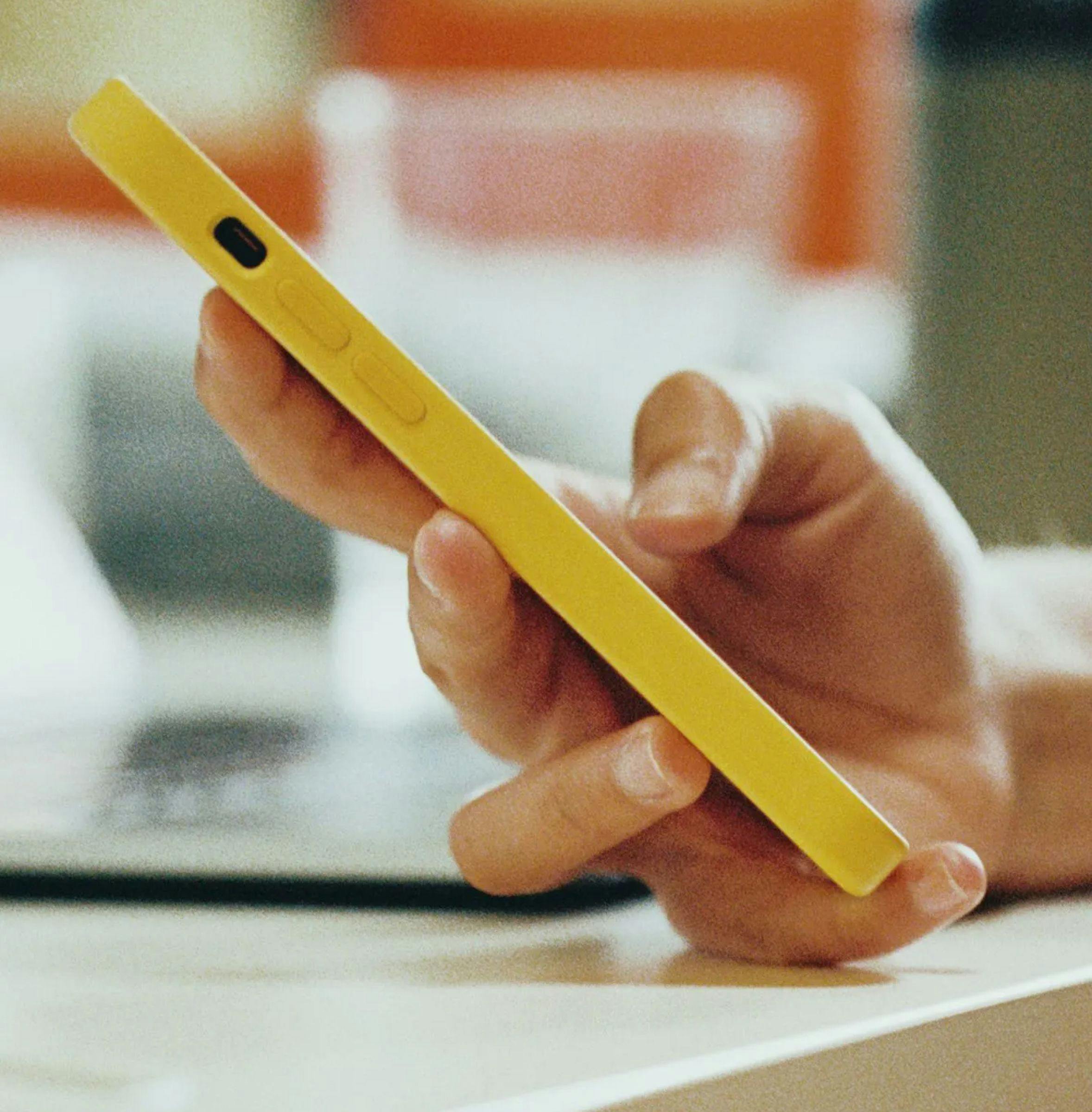 Close-up of a person's hand holding a yellow mobile phone