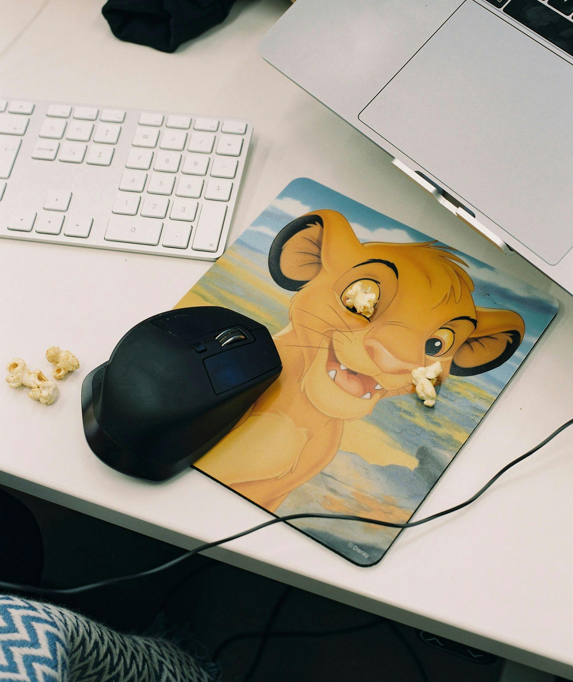 Computer, keyboard, mouse and mousepad with pieces of popcorn